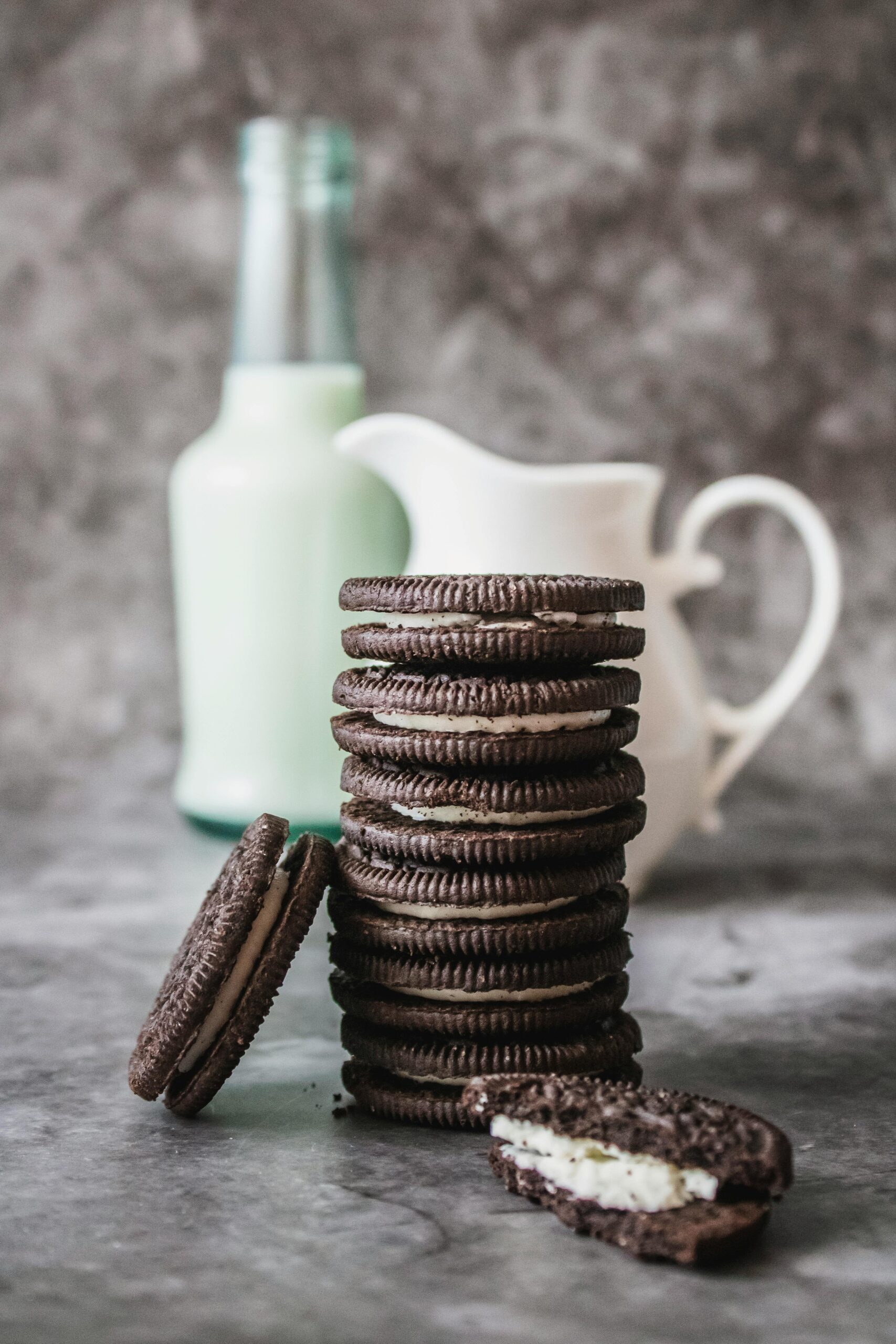 Delicious stack of chocolate cookies and milk bottle on a marble surface, perfect for an indulgent breakfast.