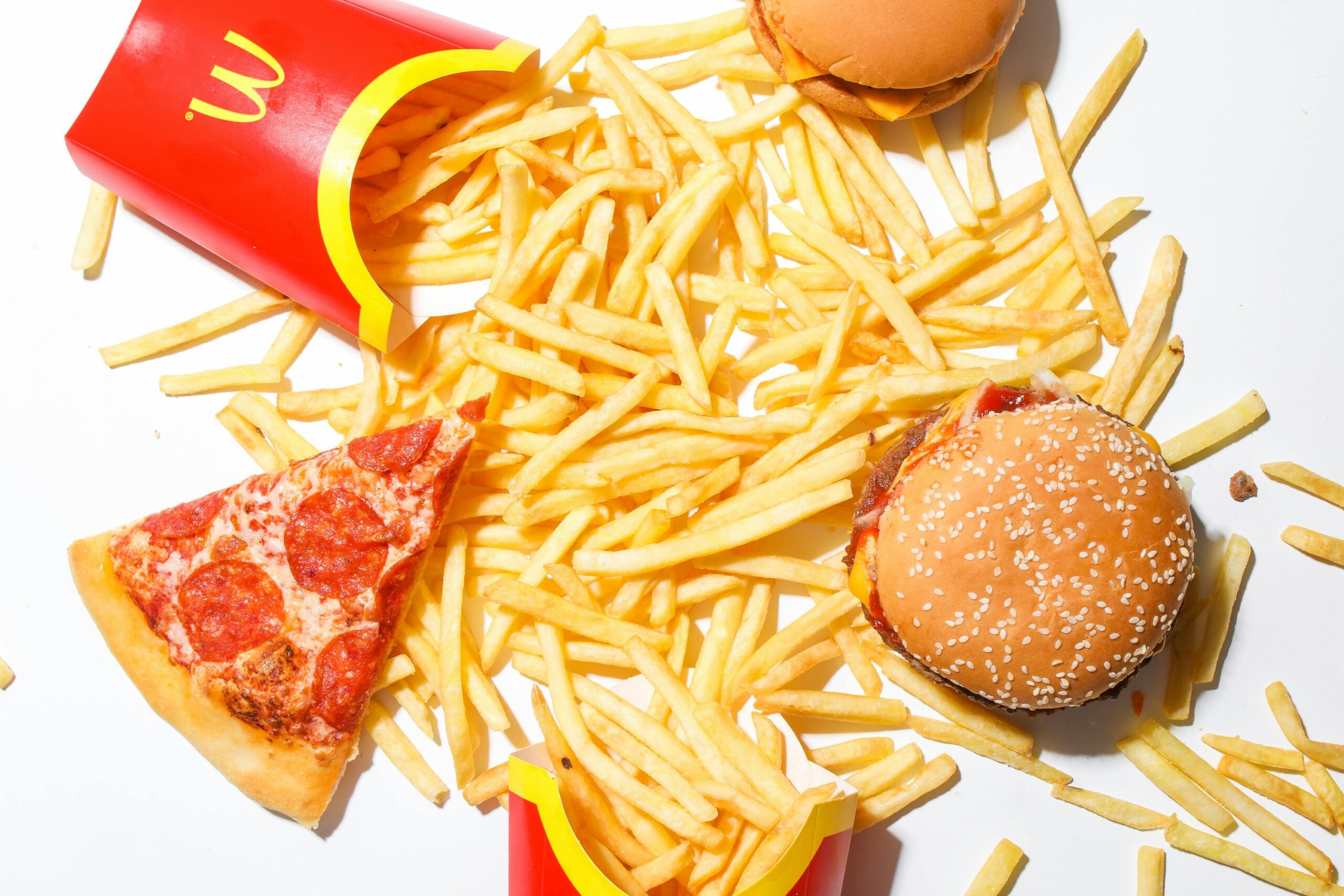 A tantalizing spread of burger, fries, and pizza showcasing classic fast food indulgence.